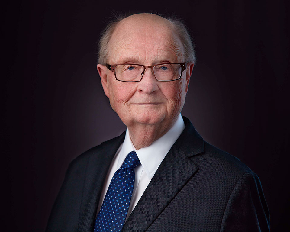 Glen Bell in a dark suit and blue tie. A professional head shot.